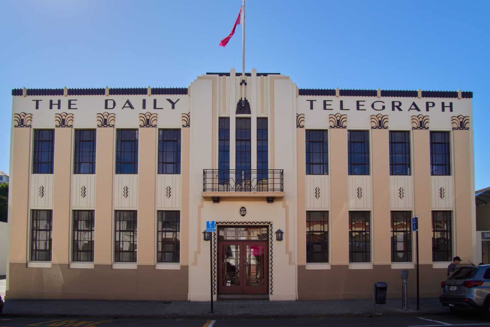 The cream and pink Daily Telegraph Building in Napier, New Zealand, with The Daily Telegraph in dark capitals, fan motifs and a stepped central bay with a balcony