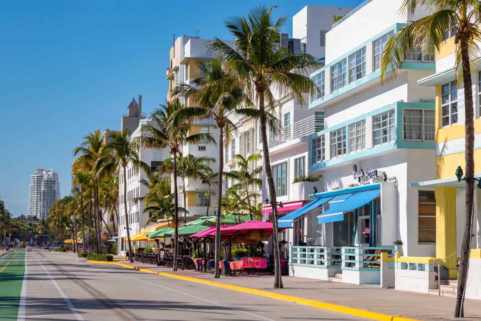 Pastel Art Deco hotels with blue awnings and palm trees lining Ocean Drive in the Miami Beach Art Deco Historic District under a clear blue sky