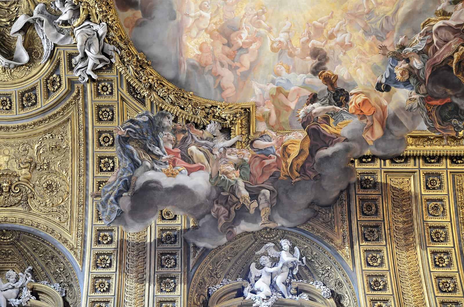 Ceiling of the Chiesa del Gesù in Rome, where Baciccio's fresco of clouds and figures spills over its gilded frame onto the coffered vault and white stucco angels