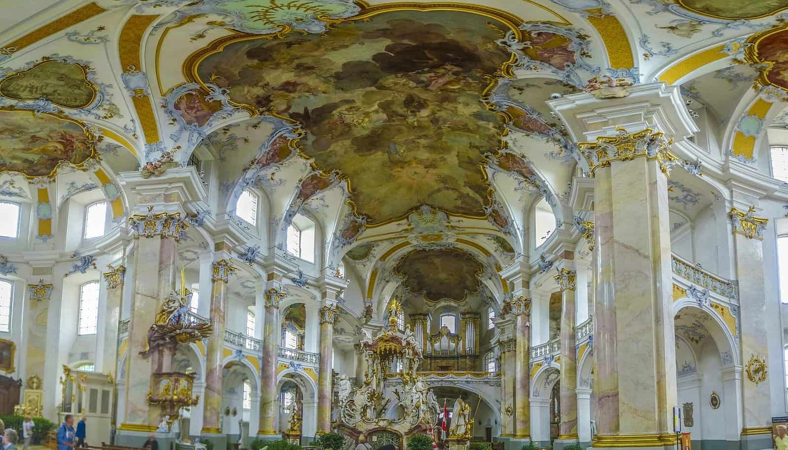 Wide interior view of the Basilica of Vierzehnheiligen in Franconia, Germany, with white and pink marbled columns, gold stucco, frescoed oval vaults and the central pilgrimage altar