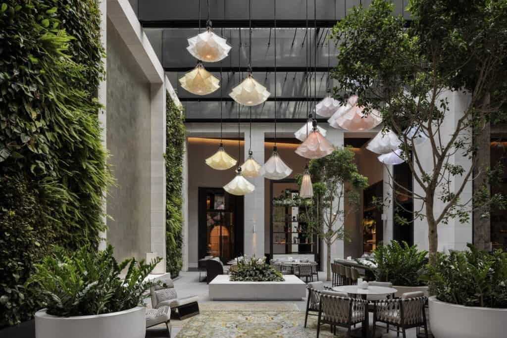 Aperture courtyard at Capella Sydney with a green wall, trees and a floating kinetic sculpture under a glass roof