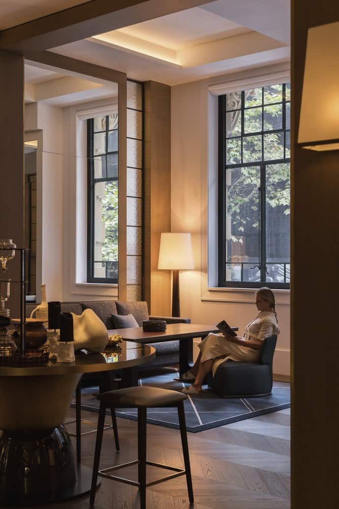 Guest lounge with tall heritage windows, armchairs and warm lamps at Capella Sydney