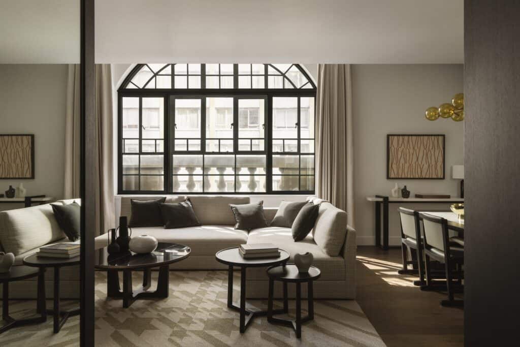 Suite living room at Capella Sydney with arched heritage window, cream sofas and a dark timber portal