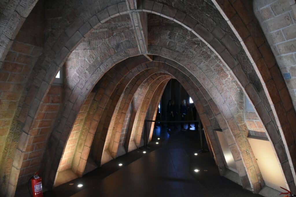 Attic of Casa Milà, the Espai Gaudí, a corridor of brick catenary arches lit softly from below with display cases receding into the darkness