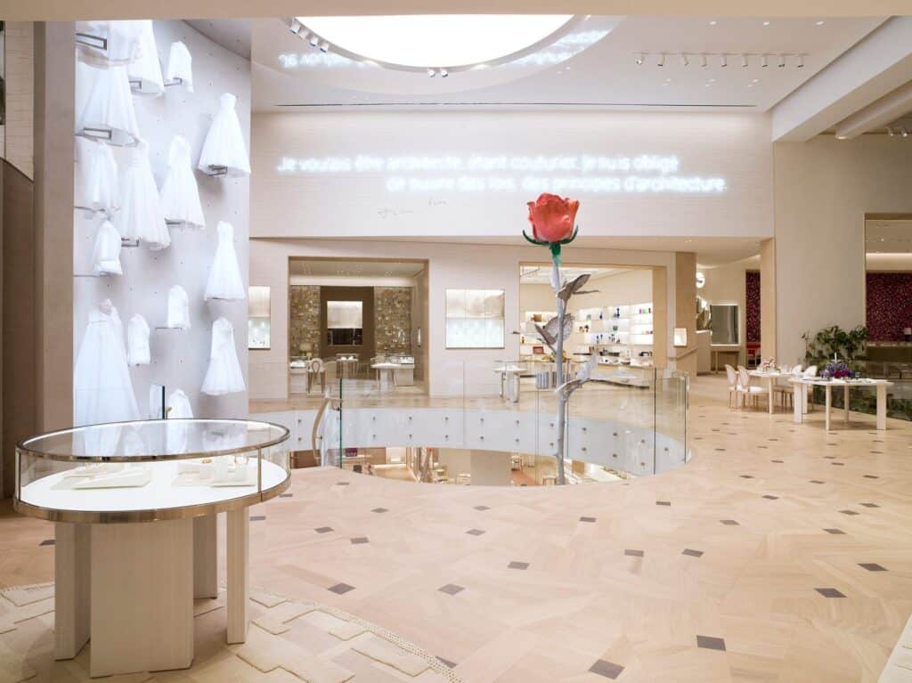 Isa Genzken's giant red Rose II rising from the stairwell at Dior 30 Montaigne, beside an inlaid stone and parquet floor, a neon quotation by Christian Dior about architecture and white dresses on the wall