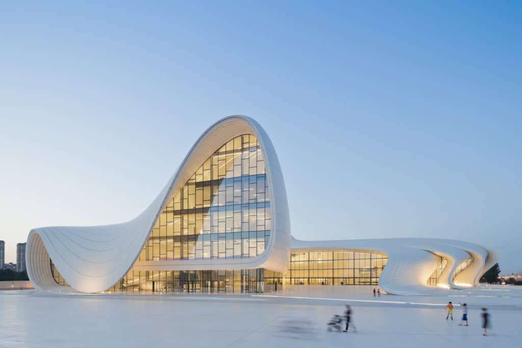 White undulating shell of the Heydar Aliyev Center glowing at dusk over the plaza, Baku