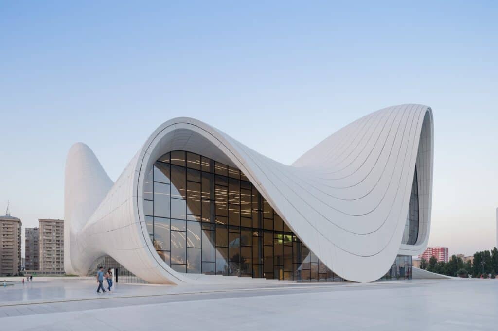 Sweeping white curves and lit glass facade of the Heydar Aliyev Center at blue hour