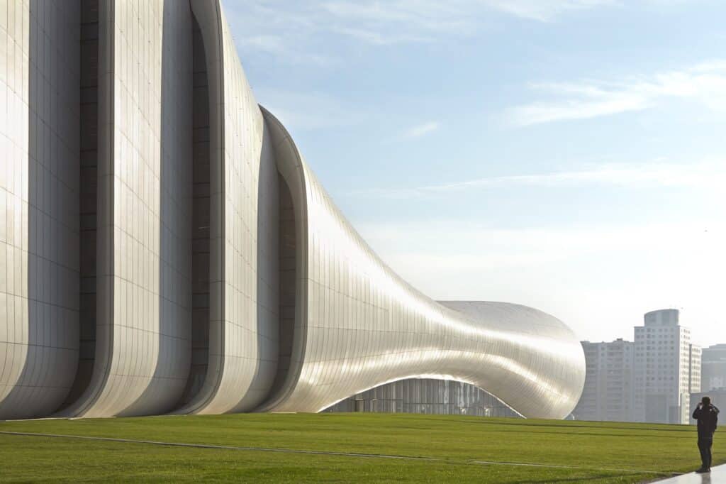 Daytime view of the Heydar Aliyev Center white folds rising above a green lawn