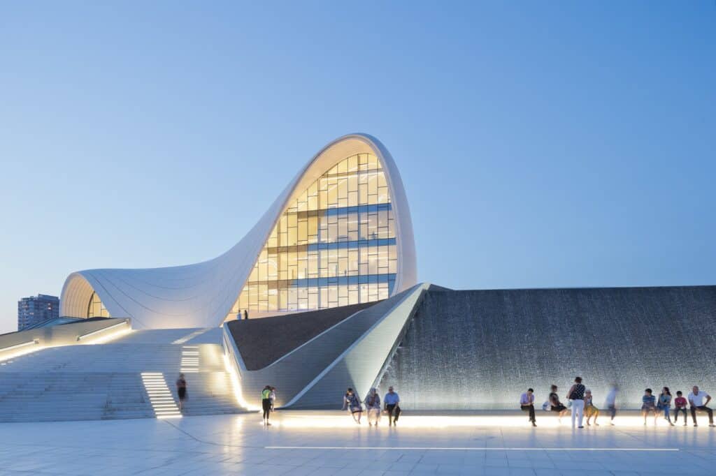 Illuminated plaza stairs and water wall before the Heydar Aliyev Center at dusk