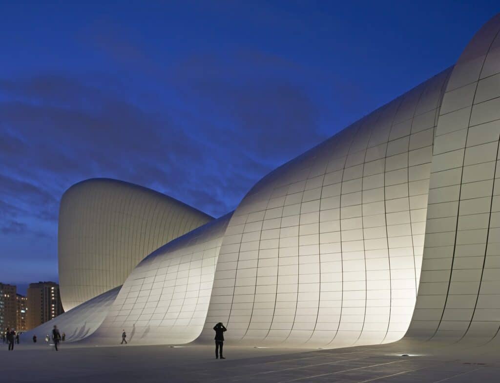 Ground-lit white peaks of the Heydar Aliyev Center against a deep blue evening sky