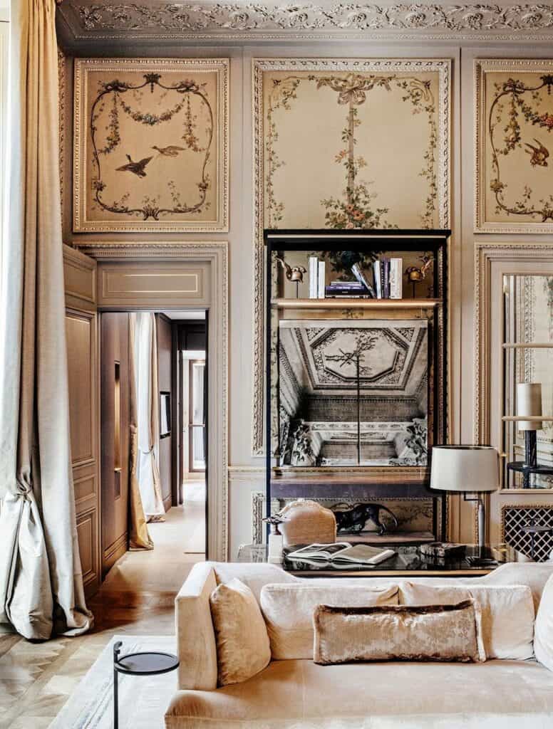 Salon at Hôtel de Crillon with carved and painted ornamental wall panels, a central bookcase niche, a long cream velvet sofa and a parquet floor