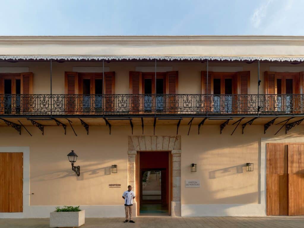Kimpton Las Mercedes Hotel in Santo Domingo's Ciudad Colonial, a restored two-storey colonial facade on Calle Las Mercedes with a wrought-iron balcony, timber shutters and a stone-framed doorway
