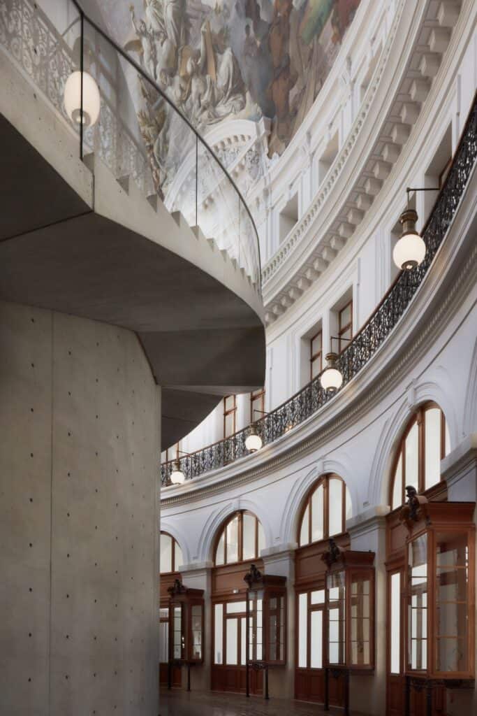 Looking up the curved concrete wall and wrapped staircase inside La Bourse de Commerce
