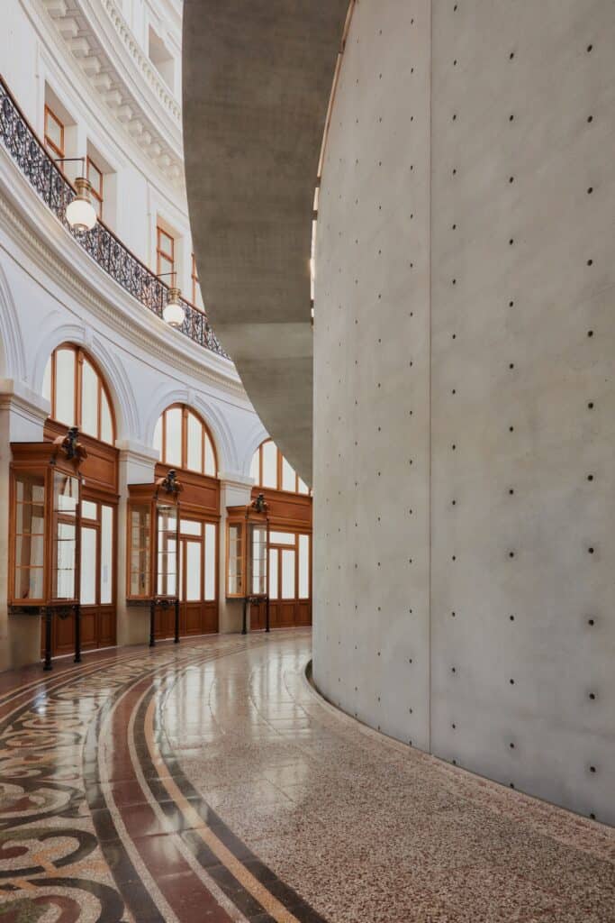 Tadao Ando concrete wall beside the mosaic floor and arched windows of La Bourse de Commerce
