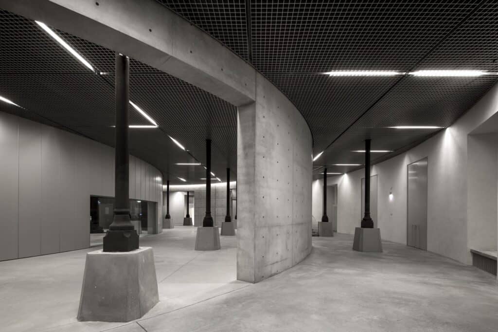 Basement foyer of La Bourse de Commerce with curved concrete wall and exposed columns