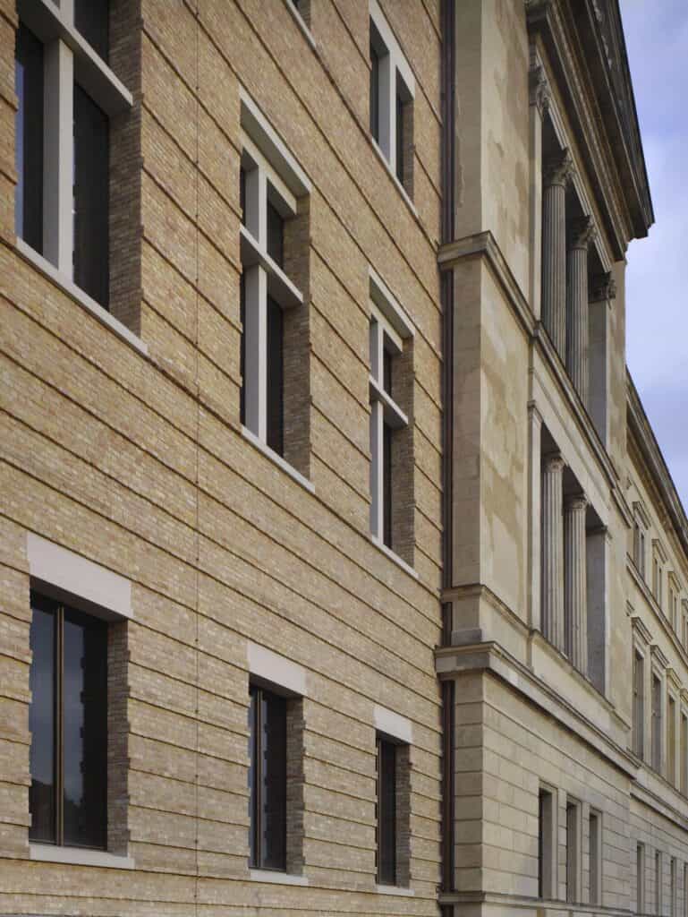 New recycled-brick wing of the Neues Museum with deep-set windows meeting the original rendered facade and its columned upper bay