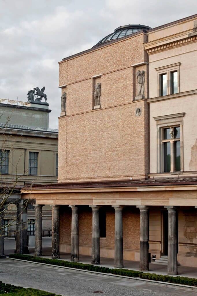 Rebuilt South Dome corner of the Neues Museum in recycled brick with statues in niches and a glazed cupola, rising above the restored stone colonnade