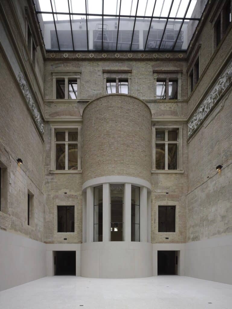 Greek Courtyard of the Neues Museum under its new glazed roof, with a curved brick apse set against the historic walls and a sculpted frieze running along the sides