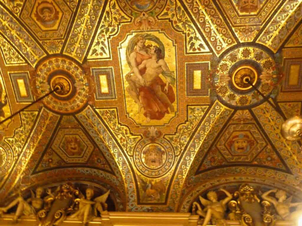 Glittering gold mosaic vault of the avant-foyer at the Palais Garnier, a painted female figure set in a panel between ornate roundels and gilded ribs
