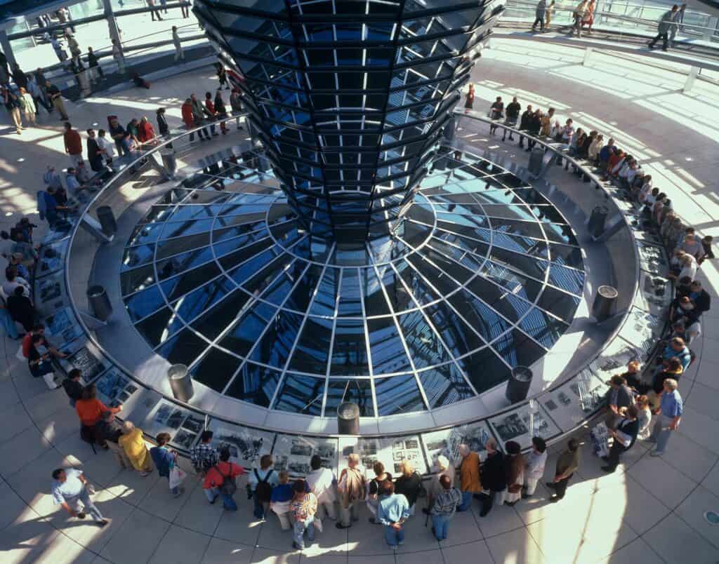 Visitors gathered around the base of the mirrored cone at the floor of the Reichstag cupola, looking down through the glazed ring into the plenary chamber below
