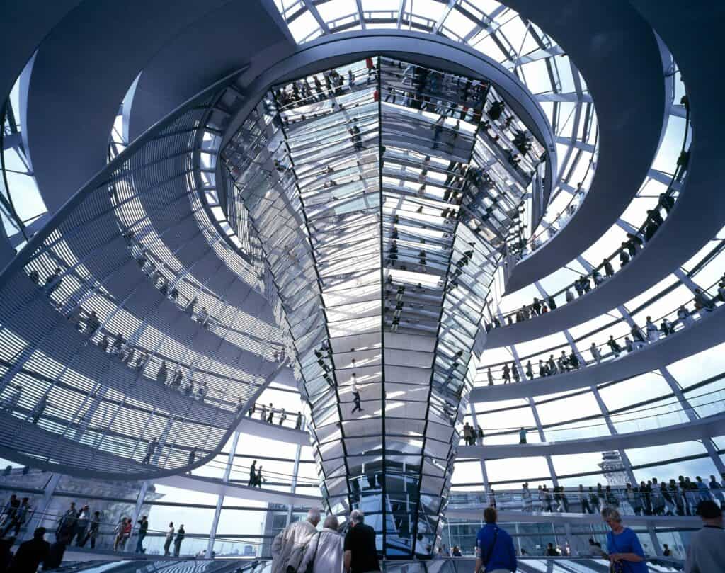 Mirrored cone of the Reichstag cupola reflecting the crowds on the spiral ramps that coil around it beneath the glazed dome and a blue sky