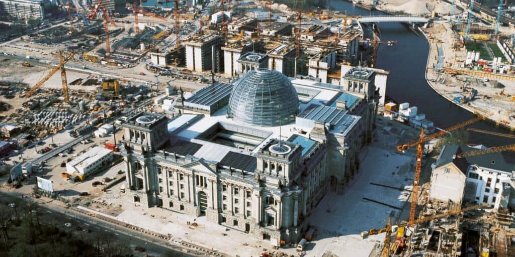 Aerial view of the Reichstag with its new glass cupola surrounded by construction cranes and building sites of the government quarter beside the River Spree
