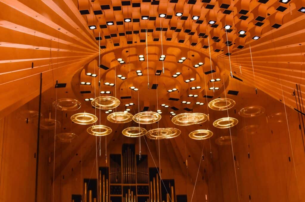 Concert Hall ceiling of the Sydney Opera House in 2019, brush box timber ribs and rows of lights fanning around a coffered crown above the acrylic acoustic rings and the pipes of the Grand Organ