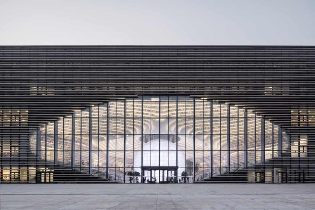 Louvred facade of Tianjin Binhai Library with an eye-shaped glazed opening revealing the glowing sphere inside