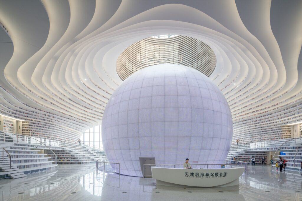 Symmetrical view of the sphere and reception desk beneath the oval skylight in the Tianjin Binhai Library atrium