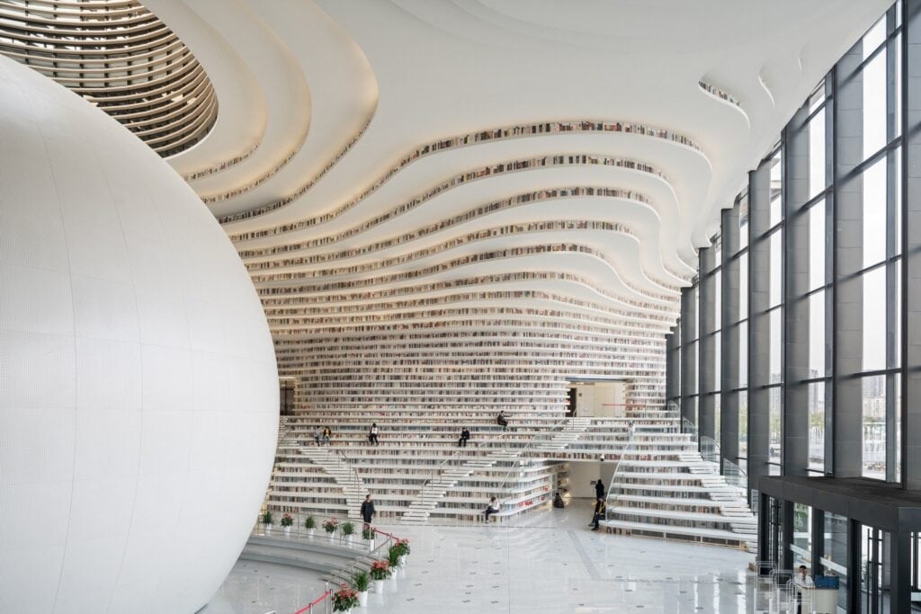Side of the white sphere, cascading bookshelf terraces and full-height glazing in the Tianjin Binhai Library atrium