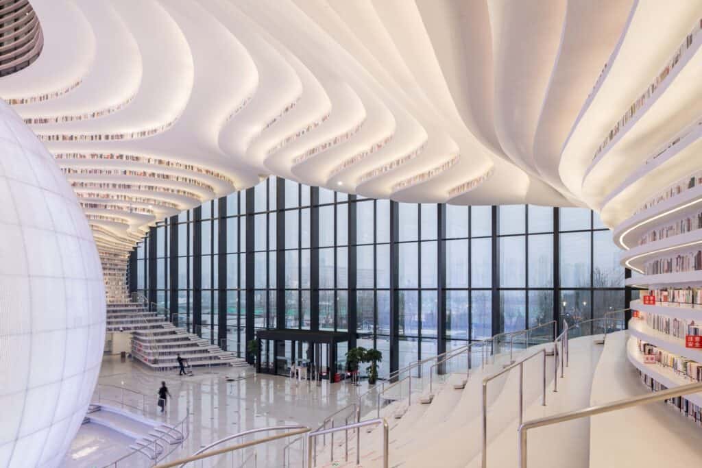 Atrium of Tianjin Binhai Library seen from the upper terraces toward the glazed entrance, the sphere at the edge of frame
