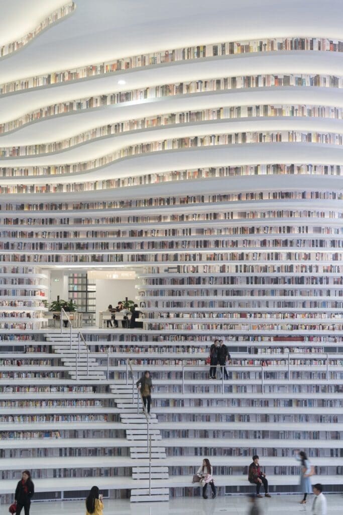 Full-height bookshelf terraces and staircase leading up to a reading room niche at Tianjin Binhai Library
