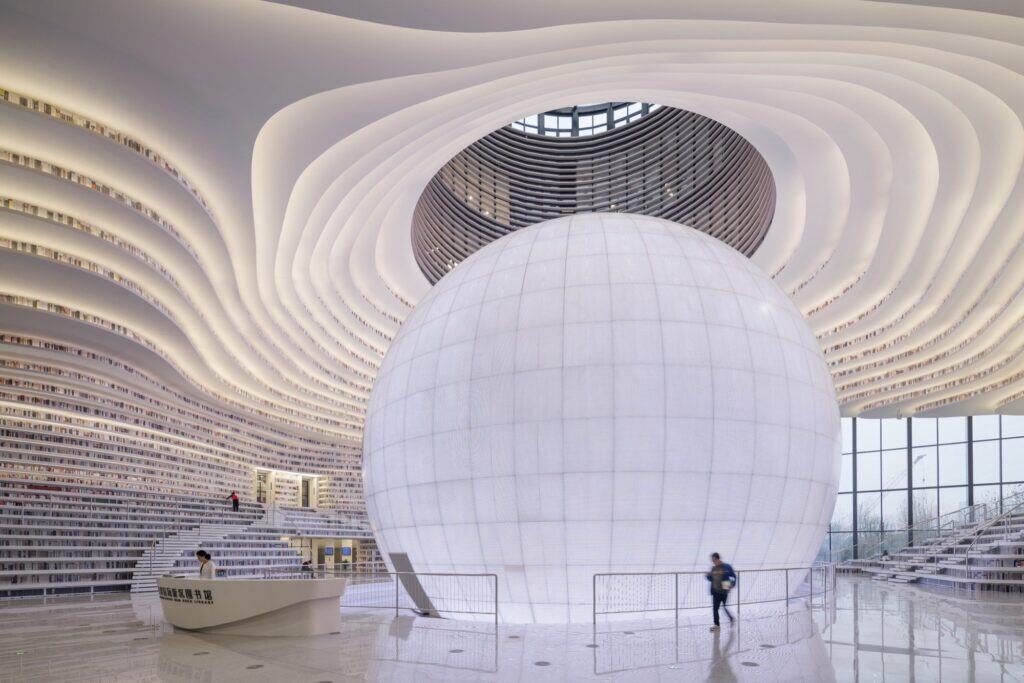 Glowing sphere of Tianjin Binhai Library beneath the louvred oval skylight, a visitor walking past